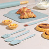 Set of pastel blue silicone baking utensils and board shown with pastries.