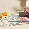 Whisk with cream, croissants and jam jar in kitchen setting