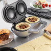 Silver pie maker shown making two meat pies with rolled pastry and filling.