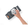 Grey hand-held vegetable slicer with safety guard in use, shown slicing carrots