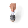 Hand pressing grey manual food chopper with chopped nuts inside, shown from above.