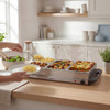 Buffet server with three hot food trays and visible steam in a modern kitchen