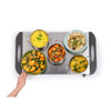 Indian meal dishes on a warming tray, including rice, curry, dal, naan, and vegetables