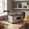 Silver deep fat fryer with basket on kitchen counter, steam rising, ideal for home cooking
