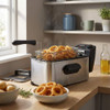 Stainless steel deep fryer with basket of cooked onion rings on kitchen counter