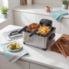 Stainless steel deep fryer with basket of chips and fish, UK kitchen setting
