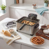 Stainless steel deep fat fryer with fresh churros in kitchen setting, prep items beside