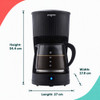 Black filter coffee maker with glass jug on kitchen counter, shown with breakfast.