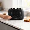 Black 4-slice toaster on counter, hand placing toast by Progress brand
