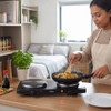 Double hot plate in use cooking stir fry noodles on kitchen counter in a compact flat