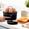 Black egg poacher with cooked egg, toast and coffee on kitchen counter