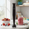 Black hand blender on kitchen counter with smoothie jar and bowl of berries