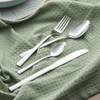 Set of silver cutlery including knife, fork, and two spoons on green textured cloth