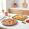 Round pizza tray and oven tray with chips on a kitchen worktop
