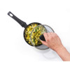 Non-stick saucepan with glass lid, shown with pasta and herbs, hand lifting lid