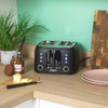 Black 4-slice toaster on kitchen counter, with bread toasting, butter, and chocolate spread