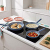 Set of three non-stick frying pans cooking chicken, creamy sauce, and tomatoes on a hob.