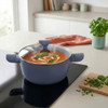Blue non-stick casserole pot with glass lid, shown cooking tomato soup on a hob.