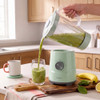 Green blender pouring kiwi smoothie into a glass