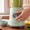Green blender base with smoothie jug and hand turning the control dial