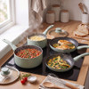 Set of three mint green saucepans in kitchen, omelette in frying pan, food visible