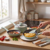 Set of three mint green saucepans in kitchen, omelette in frying pan, food visible