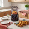 Black deep fat fryer with basket of cooked onion rings in kitchen setting