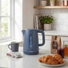 Blue electric kettle being filled at kitchen sink, matching blue toaster on counter