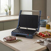 Electric grill with steak and skewers cooking on kitchen counter