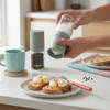 Green salt and pepper grinder set in use, seasoning poached eggs on toast at breakfast table