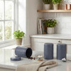 Set of three blue kitchen canisters for tea, coffee and sugar on white countertop