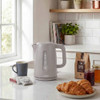 Light grey electric kettle on kitchen counter with mug, tea bags, croissants, and coffee bag