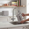 Grey electric kettle being filled at kitchen sink, matching toaster on counter behind
