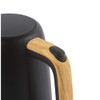 Close-up of black kettle with wood-effect handle and power button, studio background