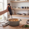 Hand blender blending soup in grey pot on kitchen counter