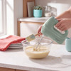 Green electric hand mixer with beaters attached, extra dough hooks beside on white background