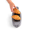 Hand placing croissants in grey toaster, showing bread warming feature.