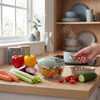 Manual food chopper with chopped vegetables on kitchen counter, hand pulling handle