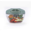 Manual food chopper with green lid, filled with chopped vegetables, front view