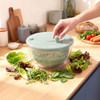 Green plastic salad spinner basket in clear bowl, top view