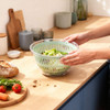 Hand using green manual salad spinner, top view