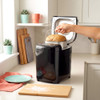 Black bread maker with freshly baked loaf being lifted out