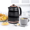 Black and rose gold kettle on table with pastries and cup of tea