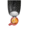 Black leopard print kettle pouring hot water into a red mug with tea bag, top view