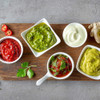 Jar of fresh green herb pesto on wooden board