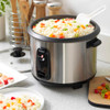 Hand pouring rice into silver electric rice cooker on kitchen counter