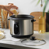 Hand pouring rice into silver electric rice cooker on kitchen counter