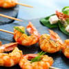 Cooked king prawns with herbs and garlic on skewers, served with salad.