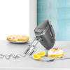 Silver hand mixer with beaters, lemon meringue pie and lemons on kitchen worktop