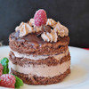 Chocolate layer cake with cream filling, chocolate shavings, and raspberry topping